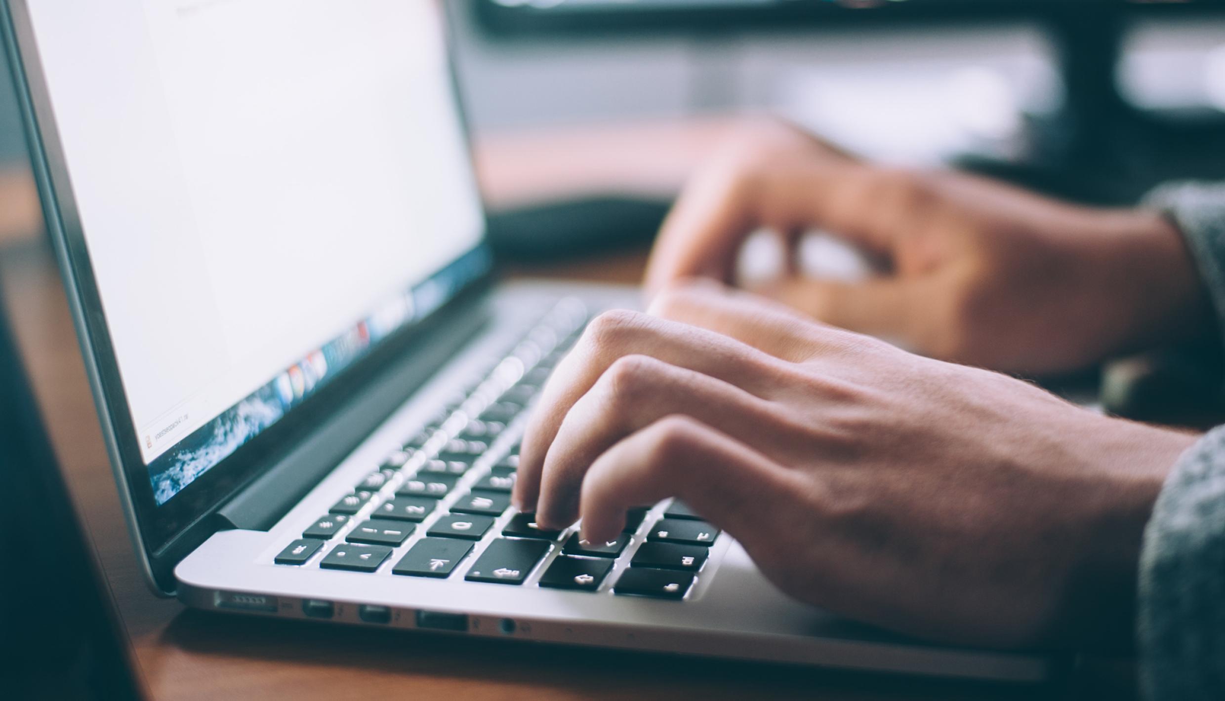 Hands typing at a laptop computer