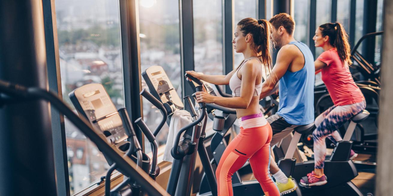 two women and one man using exercise machines at the gym.